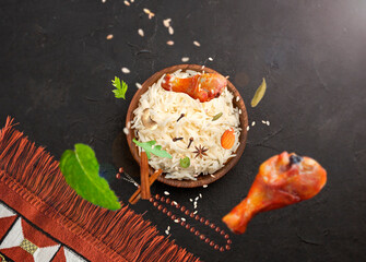 Arabic rice in a wooden bowl with chicken and spices - top view -Black background