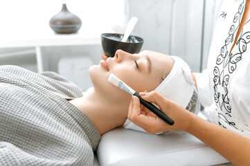 Side view of a caucasian relaxed woman lying in a salon with her eyes closed during a beauty...