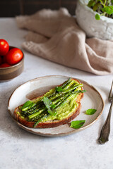 Toasted sourdough bread with grilled asparagus, avocado and herbs for single serving. Avocado toast. Breakfast idea. Healthy food concept.