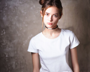 Mockup, template of a white t-shirt on a young beautiful girl on a gray background. Studio photo