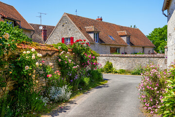 Fototapeta na wymiar Street decorated with colorful flowers in Yèvre le Châtel, a medieval village located in the French department of Loiret, Centre Val de Loire, France