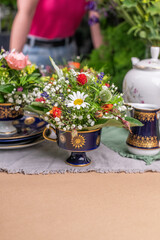 Frische Blumen arrangiert in einer alten Kaffeetasse, Blumengesteck in Vintage Geschirr, Tasse mit Blumen gefüllt, Dekoration für den Tisch