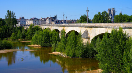 Fototapeta premium George V bridge crossing the Loire river in Orléans in the Loiret department in Centre-Val de Loire, France - Arched masonry bridge built in the 17th century used by the road and the tramway