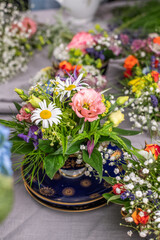 Frische Blumen arrangiert in einer alten Kaffeetasse, Blumengesteck in Vintage Geschirr, Tasse mit Blumen gefüllt, Dekoration für den Tisch