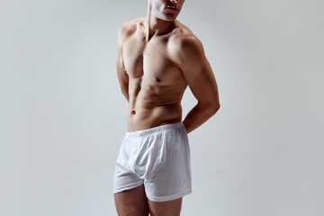 Cropped image of beautiful, muscular, fit, strong male body against grey studio background. Model...