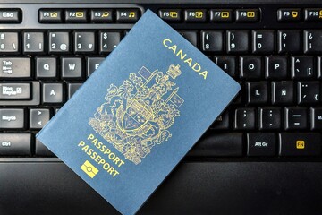 Canadian passport on a laptop keyboard. Online registration. Immigration control verifies passport...