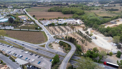 Port Grimaud with a view of the backland with construction site, garden center, trees; shops and mountains on the Cote d'azur; French Riviera, drone shot