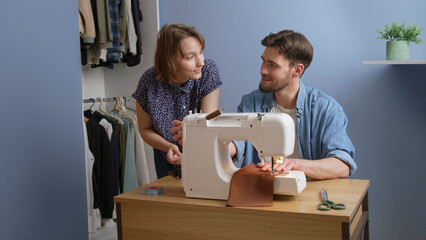 Young european woman teach caucasian man how to sew at home