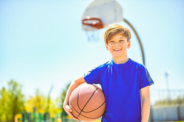 portrait of a kid boy playing with a basketball in park