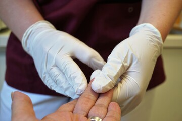 Hände von Ärztin mit weißen Gummihandschuhen halten Hand von Patientin in Arztpraxis 
