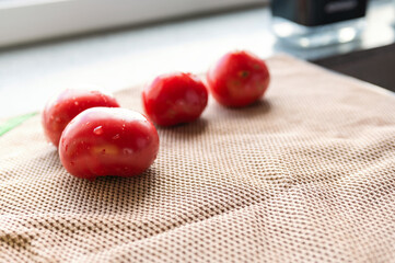 washed red tomatoes are laid out to dry on a beige waffle towel. Cooking a healthy vegetable salad