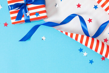 Obraz premium 4th of July, USA Presidents Day, Independence Day. Flat lay top view of patriotic wrapping paper and gift box twinkling confetti on blue background with space, promotion or greeting message, banner
