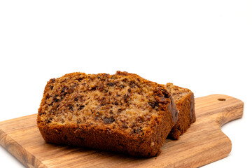 Slices of freshly baked homemade chocolate banana bread on a wooden board. Isolated on white background with copy space.