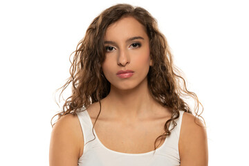 Portrait of a young serious woman with makeup and long wavy hair on a white background