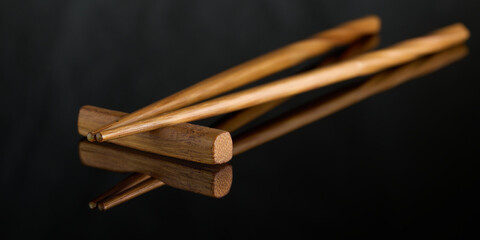 Asian traditional chopsticks on black background with mirror reflection