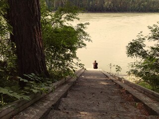 the person is sitting on the syairs by the river
