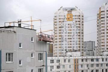 Break during work. Empty construction cradle on metal cables on the high near the wall surface on block of flats house