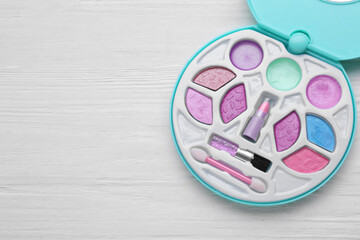 Decorative cosmetics for kids. Eye shadow palette on white wooden table, top view. Space for text