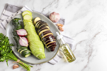 Cooking delicious ratatouille. Fresh ripe vegetables and plate on white marble table, flat lay....