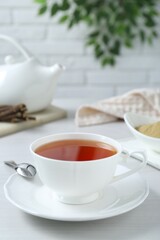 Aromatic licorice tea in cup and spoon on white table, space for text
