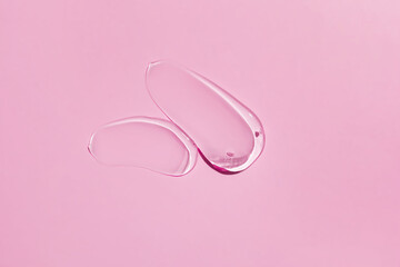 Obraz na płótnie Canvas Glycerin gel texture. Transparent serum smears on pink background. Liquid gel moisturizer with bubbles macro