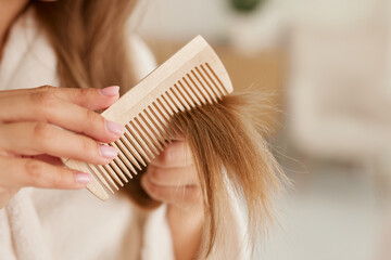 a young girl in a white coat takes care of her hair at home