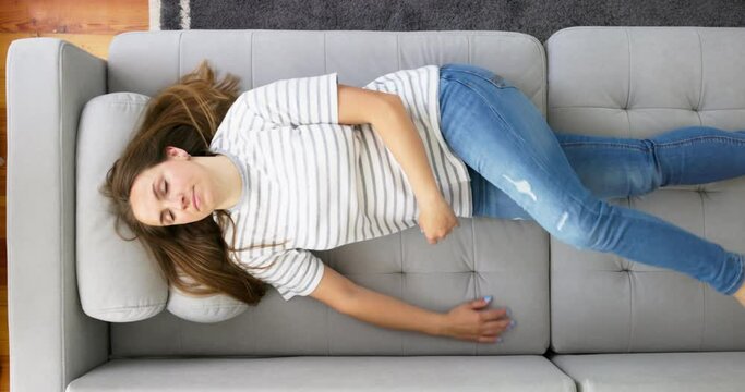 Exhausted woman falls down on sofa feeling out of energy after hard working day.