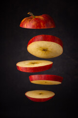 sliced red apple free flying on a dark soft background.  artistic moody close-up photo. selective focus