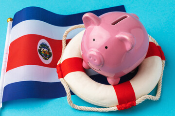 Piggy bank, lifebuoy and flag on a blue background, a concept on the theme of saving the economy of...