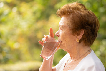 senior drinking water in summer outdoors - Powered by Adobe