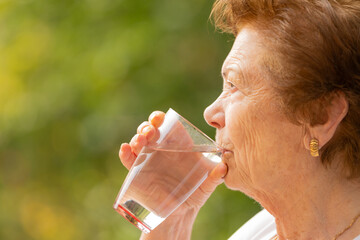 senior drinking water in summer outdoors