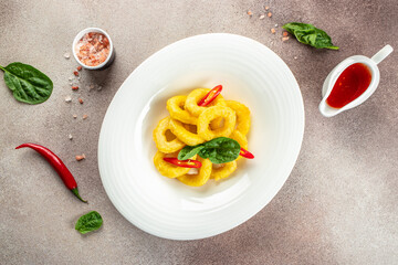 baked breaded calamari rings served with sweet chilli sauce on a light background. banner, menu, recipe place for text, top view