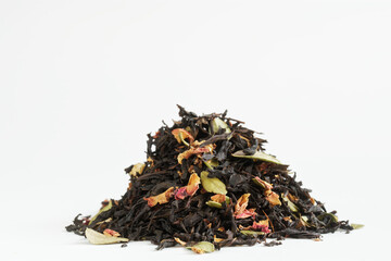 Heap of black flavored tea, with the addition of fruits, berries and flower petals. White background. Macro. Photo. Selective focus