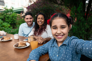 young daughter taking selfie with mobile outside in the garden