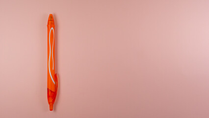 an orange pen lies on a pink background. view from above