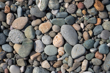 Rounded colorful stones on the sea shore. Background with natural pebbles, texture wallpaper. View from above.