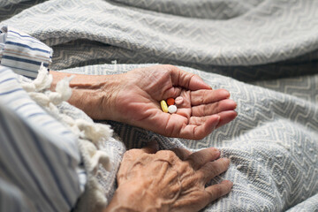 Old woman holding medicine and taking vitamins to heal. Colorful pills in old woman hand. Care for...