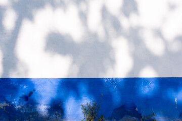 White and blue wall with texture and shadows.