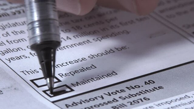 Close up of person voting to maintain a tax increase on ballot.