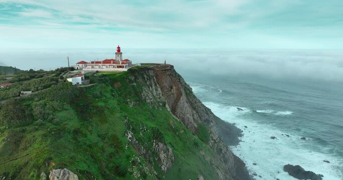 Aerial view pf the most western point of the European continent - Cabo da Roca, Portugal. Drone flies over the Atlantic ocean coast, rocky formations and the beach called Praia da Ursa.