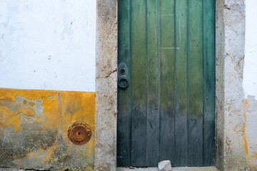 Green door on a white and yellow wall in an ancient european town
