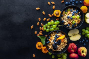 Two healthy breakfast bowl with ingredients granola fruits Greek yogurt and berries on dark...