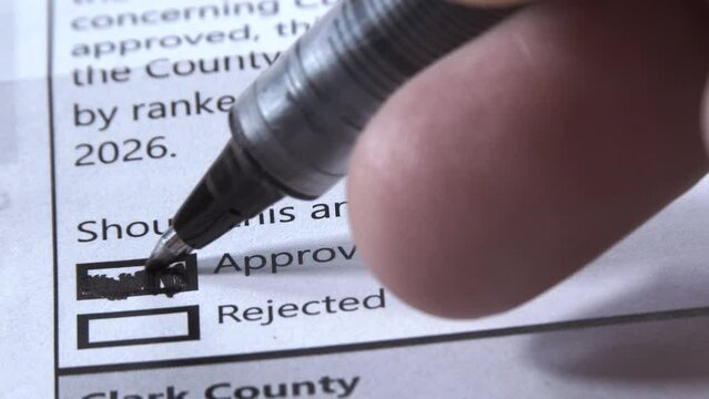 Person votes to approve amendment on ballot for ranked voting, close up.