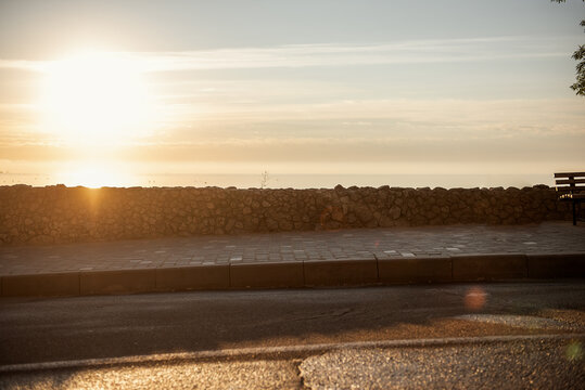 Sunny promenade by the sea at sunrise. The sidewalk is paved. Road by the sea for jogging, sports. - Powered by Adobe