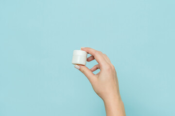 Jar of cream or ointment in hand. Packaging cosmetic product