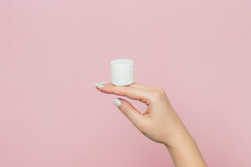 Plastic jar or bottle with cream (ointment) in woman's hand. Facial care, bottle with cosmetic product