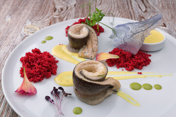 Fried herring fillet with sauce on a white plate