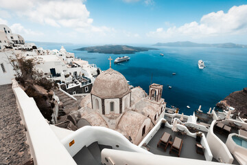 Fototapeta premium magical and sun covered city of thira, ideal for vacation and travel during hot summer days, on the horizon the sea and beautiful roofs of houses, travel and relaxation in greece,white and blue 