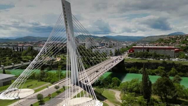 Aerial orbiting shot of the Millennium Bridge, a cable-stayed bridge and the Moracha river in Podgorica, Montenegro