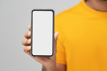 Closeup of man hand holding mobile phone with empty display, isolated on gray background, mockup